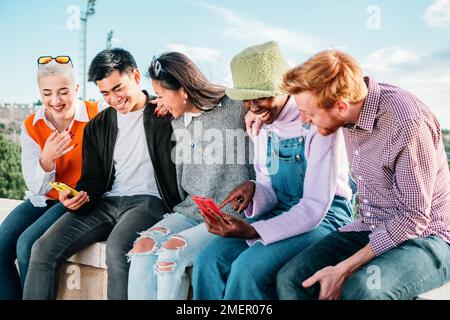 Cinq amis multiraciaux regardent des vidéos sur les réseaux sociaux ensemble et s'amusent. photo de haute qualité Banque D'Images