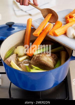 Ingrédients (carottes) ajoutés à la casserole-au-feu Banque D'Images