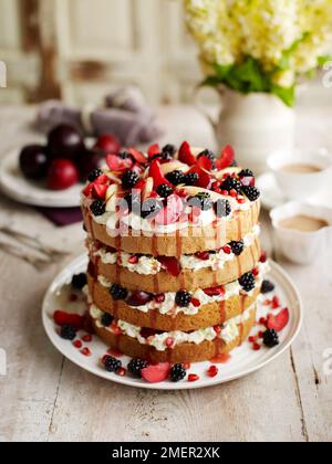 Gâteau à plusieurs niveaux de poire et de mûre, rempli de crème fouettée et de cassis, sur une table en bois Banque D'Images