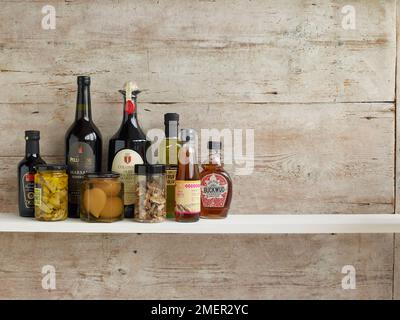 Divers ingrédients de cuisson en bouteilles et en pots sur étagère, fond de bois Banque D'Images