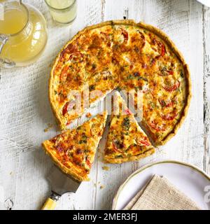 Tarte aux tomates et à la dijon avec une croûte de parmesan et de basilic, deux tranches coupées à l'écart du reste Banque D'Images