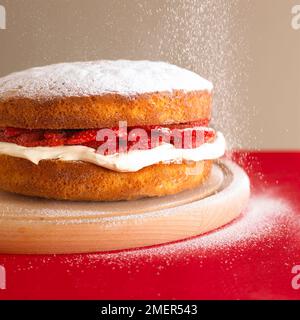 Gâteau éponge à la fraise et à la crème saupoudrés de sucre glace Banque D'Images