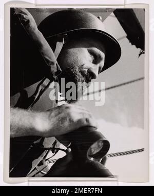 Les yeux sur les Skies. Cette image représente un envahisseur barbu de la Garde côtière, une figure frappante dans un casque et un gilet de sauvetage, qui balaie le ciel à la recherche d'avions japonais. Banque D'Images