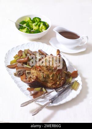 Rôti d'agneau servi sur un plat, sauce et brocoli Banque D'Images