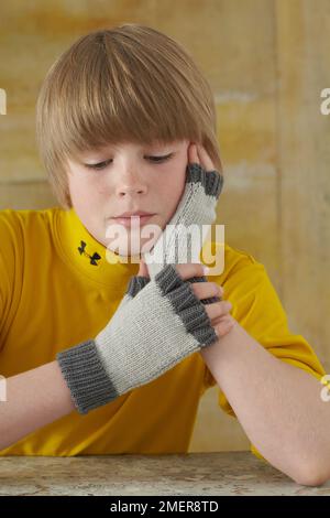 Garçon portant des gants sans doigts Banque D'Images