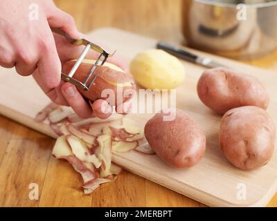 Avec éplucheuse de pommes de terre peler Banque D'Images