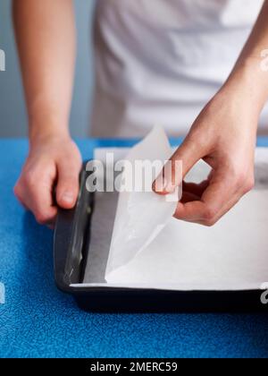 Garniture beurrée de deux feuilles de papier de cuisson, pour faire des barres de muesli Banque D'Images