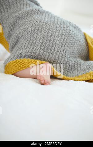 Bébé fille rampant avec une couverture tricotée à capuche dans le dos, 9 mois Banque D'Images