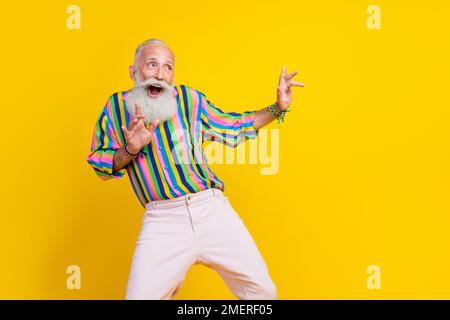 Photo de joli gars impressionné habillé chemise à rayures ayant l'amusement look vide espace isolé couleur jaune arrière-plan Banque D'Images