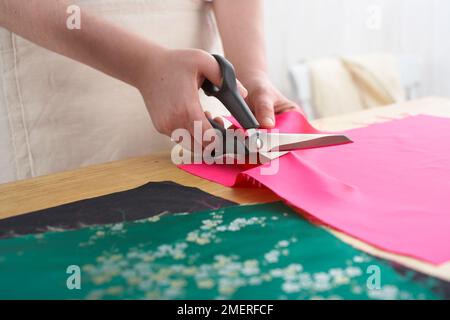 En faisant un rouleau de manucure en soie thaïlandaise, découpez un morceau chacun du tissu principal à motifs, du tissu de doublure et de l'interfaçage sur le fer Banque D'Images