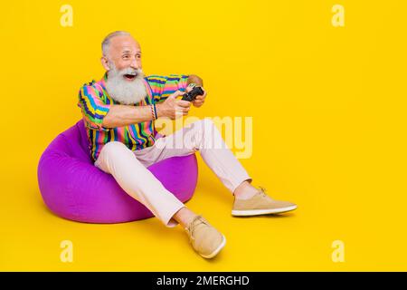 Photo pleine longueur d'un joli gars habillé rayé chemise appréciant l'espace vide isolé jaune de couleur arrière-plan Banque D'Images