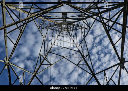 Lignes formées par la structure des poteaux haute tension coup de feu à partir d'un angle bas du fond du poteau électrique contre le ciel et les nuages blancs. Banque D'Images