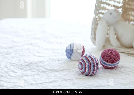 Boules de jouet en bonneterie et lapin en peluche sur un lit Banque D'Images