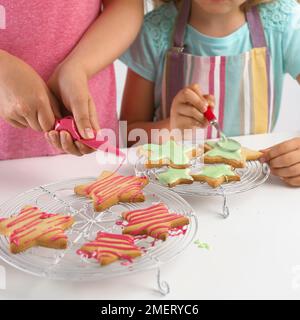 Girl decorating cookies en forme d'étoile avec du glaçage Banque D'Images