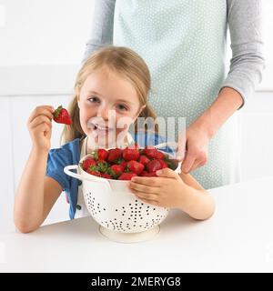 Fille et grande passoire de fraises, 5 ans Banque D'Images