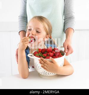 Girl holding passoire de fraises, 5 ans Banque D'Images