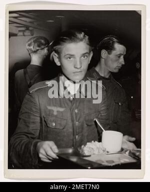 Cette photographie montre un prisonnier allemand capturé lors de l'invasion de Normandie, se déplaçant à travers la ligne chow à bord d'un transport de troupes habité par les garde-côtes. Le prisonnier, vaincu et désillusionné, est transporté dans un camp de prisonniers américain, qui fait partie de la première cargaison de prisonniers allemands de France vers l’Amérique après le jour J. Banque D'Images
