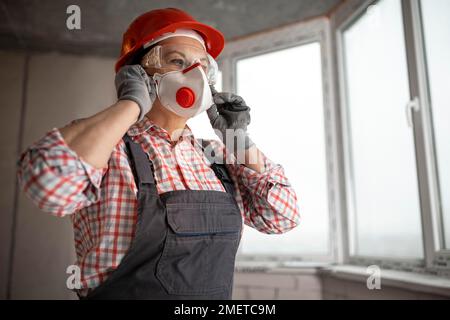 Femme de construction avec casque portant un masque facial Banque D'Images