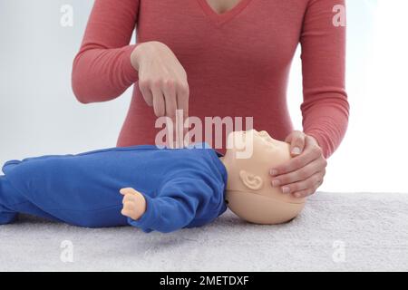 Les contrôles médicaux de premiers soins et le traitement de l'enfant inconscient, à l'aide de mannequin, appuyant sur enfant du sternum, avec les doigts, le CFCP donnant Banque D'Images