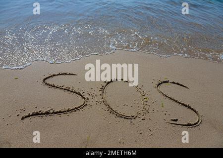 L'inscription sur le sable à la plage sos. Banque D'Images