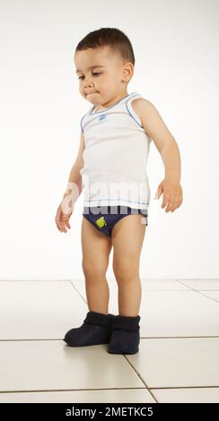 Garçon portant un gilet, un pantalon et des pantoufles, 15 mois Banque D'Images