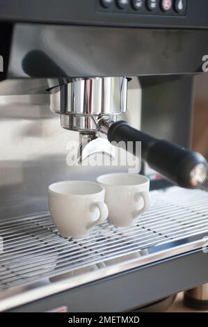 Deux tasses à espresso placées sous les becs de la machine à espresso Banque D'Images