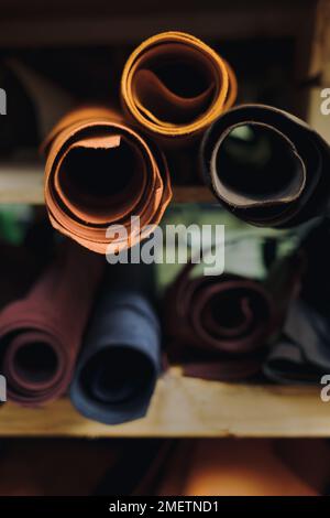 Des rouleaux de tissu et de cuir se trouvent sur les étagères du marché. Différents tissus à l'usine de confection. Copier l'espace Banque D'Images