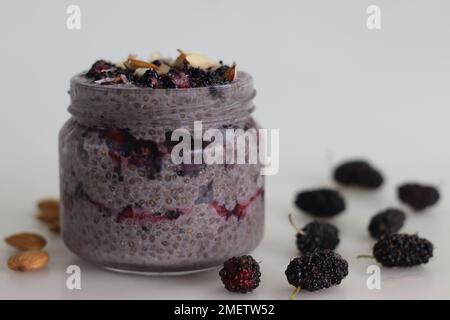 Une nuit de pudding au Chia Oats servi avec des mûres et des amandes hachées. Un petit déjeuner sain sans cuisine. Prise de vue sur fond blanc le long de W Banque D'Images