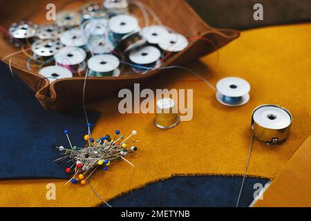 Personnalisez les accessoires de votre lieu de travail. Vue rapprochée du cuir écologique et de l'équipement de personnalisation posé sur la table. Jeu de broches, bobine pour machine à coudre Banque D'Images