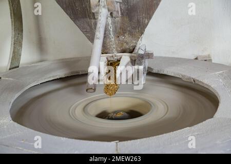 Blé tombant sur la meule à eau à Molino Grifoni, moulin produisant de la farine de pierre depuis 1696, à Castel San Niccolò, Toscane, Italie Banque D'Images