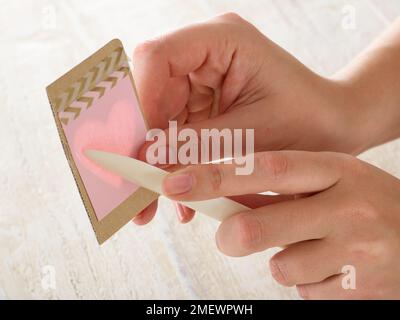 Papuraft. Papier de bricolage gaufrage étape 2. Placez la carte sur le pochoir et tracez délicatement avec la pointe de la plieuse osseuse Banque D'Images