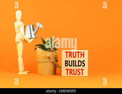 La vérité crée un symbole de confiance. Concept Words Truth construit la confiance sur des blocs de bois sur une belle table orange fond orange. Icône homme d'affaires. Entreprise Banque D'Images