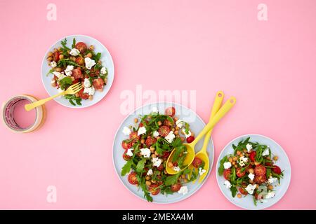Salade de pois chiches et de tomates sur fond rose Banque D'Images