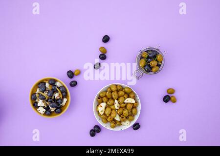 Différentes saveurs d'olives marinées sur fond violet Banque D'Images