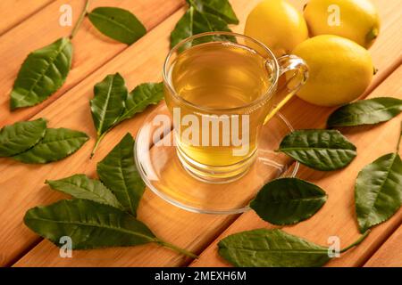 Une tasse de thé vert, de feuilles de thé et de citrons Banque D'Images