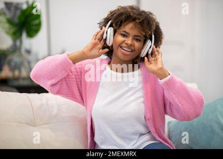 Portrait d'une femme noire heureuse écoutant de la musique à la maison Banque D'Images