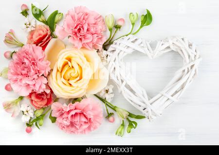 Belles fleurs printanières sur fond de bois blanc. Composition florale festive avec coeur en branches en bois. Fête de la Saint-Valentin ou fête des mères Banque D'Images