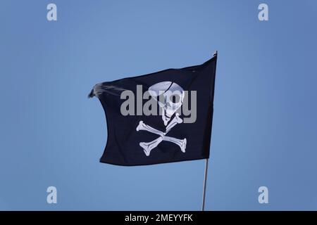 Le drapeau du pirate, Jolly Roger ou crâne et crossones contre un ciel bleu Banque D'Images