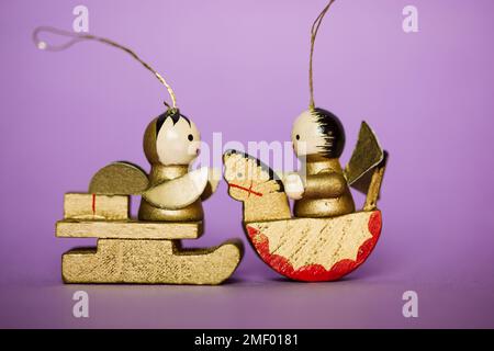 Figurines de nativité en bois minuscules vintage avec sculpture à la main et peinture sur fond violet. Jouets décoratifs d'arbre de Noël brun doré : un ange sur une h Banque D'Images