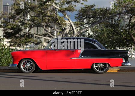 Honolulu, HI - 3 janvier 2023: Profil droit de l'automobile classique rouge et noir 1950s de Chevrolet Belair 2 portes magnifiquement restauré Banque D'Images