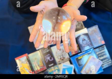 Gros plan des mains de fortune teller qui montrent une boule de marbre clair pour prédire le destin sur la carte de tarot et la lettre de cube de bois flou d'arrière-plan Banque D'Images