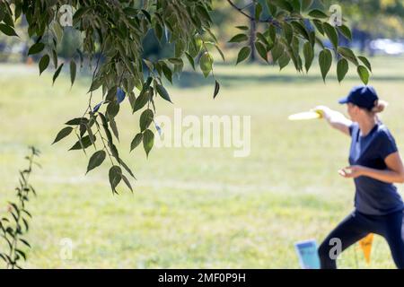 Femme jouant volant disque golf sport jeu dans le parc Banque D'Images