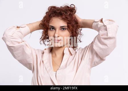 La fille corrige ses cheveux bouclés avec deux mains. Européen. Banque D'Images