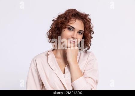 Portrait d'une fille qui sourit doucement. Cheveux bouclés courts. Banque D'Images