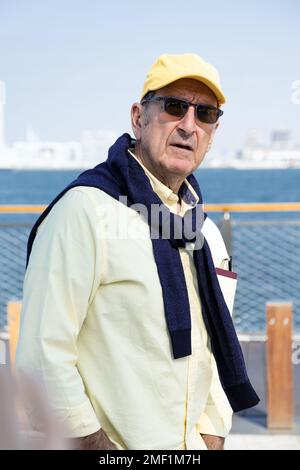 Homme senior marchant le long d'une promenade le long d'une marina. Banque D'Images