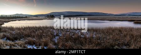 Une vue panoramique à la pause d'une journée de Penyfan Mountain sur un étang d'hiver gelé dans le parc national de Brecon Beacons, au sud du pays de Galles du Royaume-Uni Banque D'Images