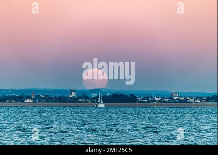 Pleine lune s'élevant au-dessus de Gosport et Portsmouth depuis Woodside Bay, Wootton, Isle of Wight. Banque D'Images