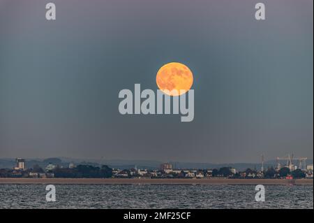 Pleine lune s'élevant au-dessus de Gosport et Portsmouth depuis Woodside Bay, Wootton, Isle of Wight. Banque D'Images