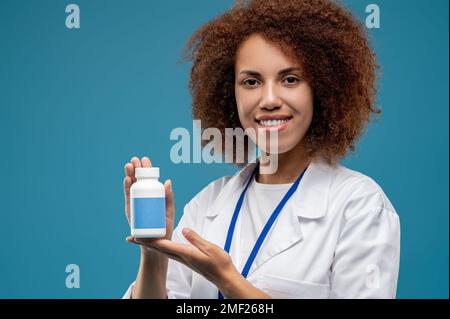 Jeune femme médecin avec bocal de vitamines dans les mains Banque D'Images