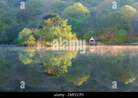 Réflexions calmes dans le lac avec une tour de bateau rustique à Rydal Water dans le Lake District, Royaume-Uni. Banque D'Images